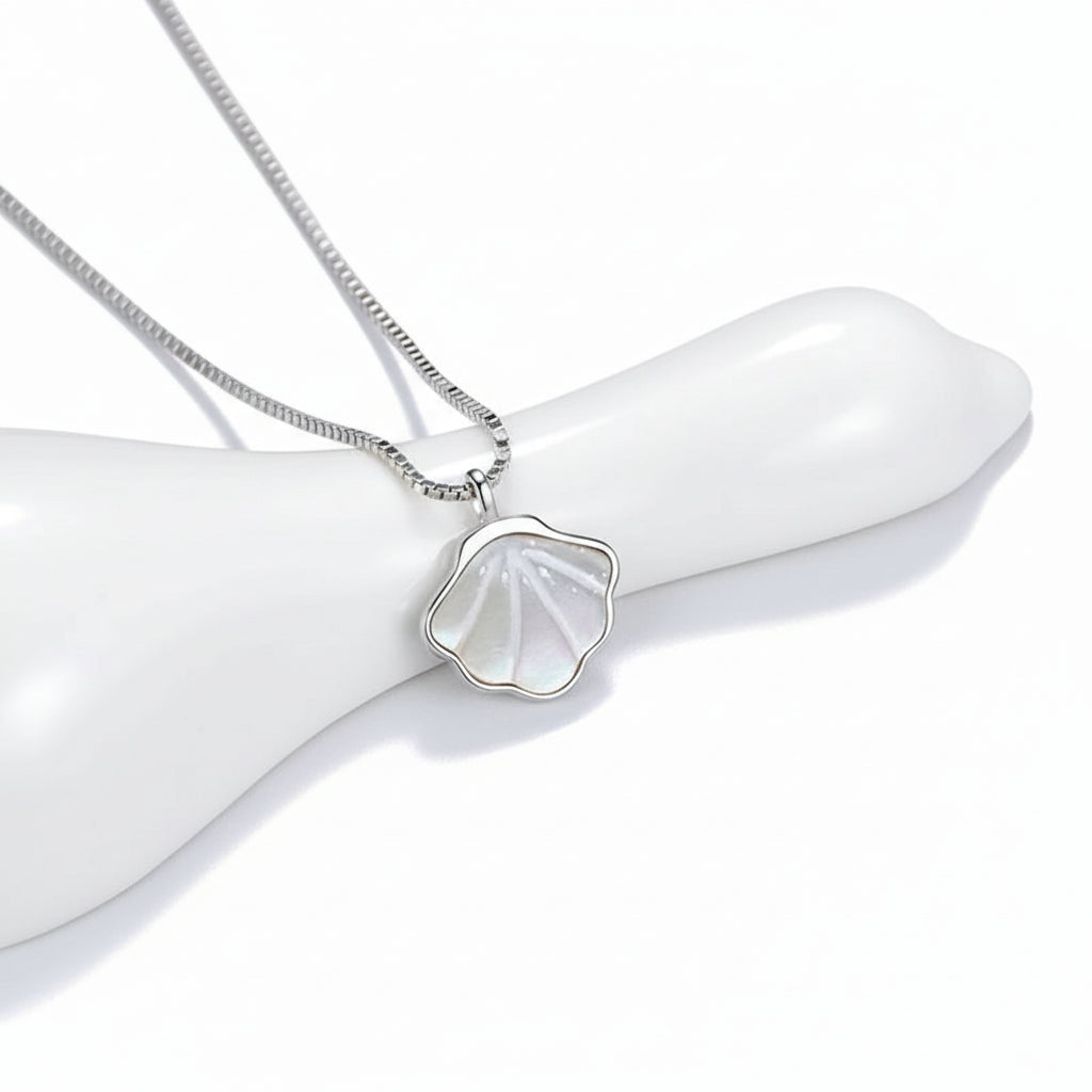Shell-shaped pendant on a chain against a light gray background