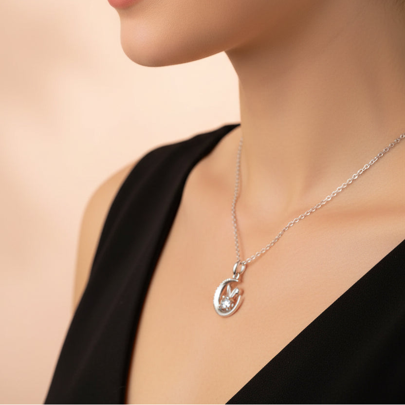 Close-up of a woman wearing a silver necklace with a pendant on a beige background