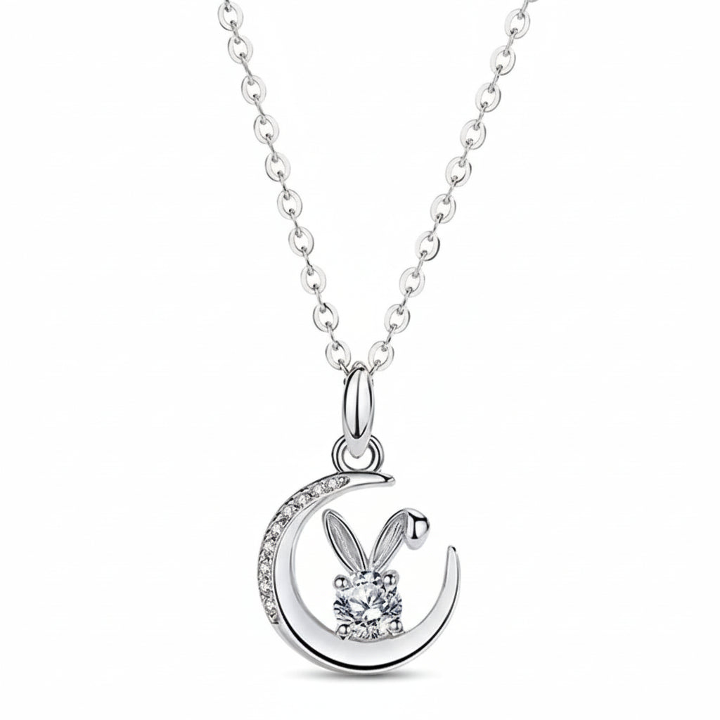Silver necklace with a bunny and moon pendant on a soft pink background