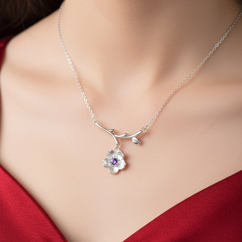 Silver necklace with a floral pendant featuring a purple gemstone on a white background